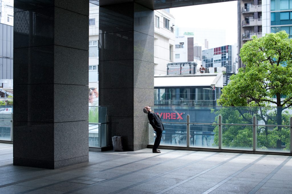 A man is excercizing and stretching in Shinjuku